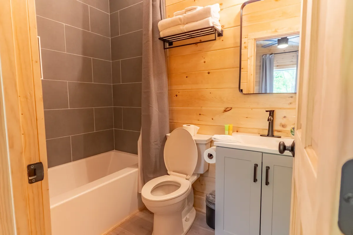 A bright, modern bathroom with a standalone bathtub, sink, toilet, and neatly arranged towels. The space feels refreshing and inviting, ideal for self-care and relaxation after a day of adventure.