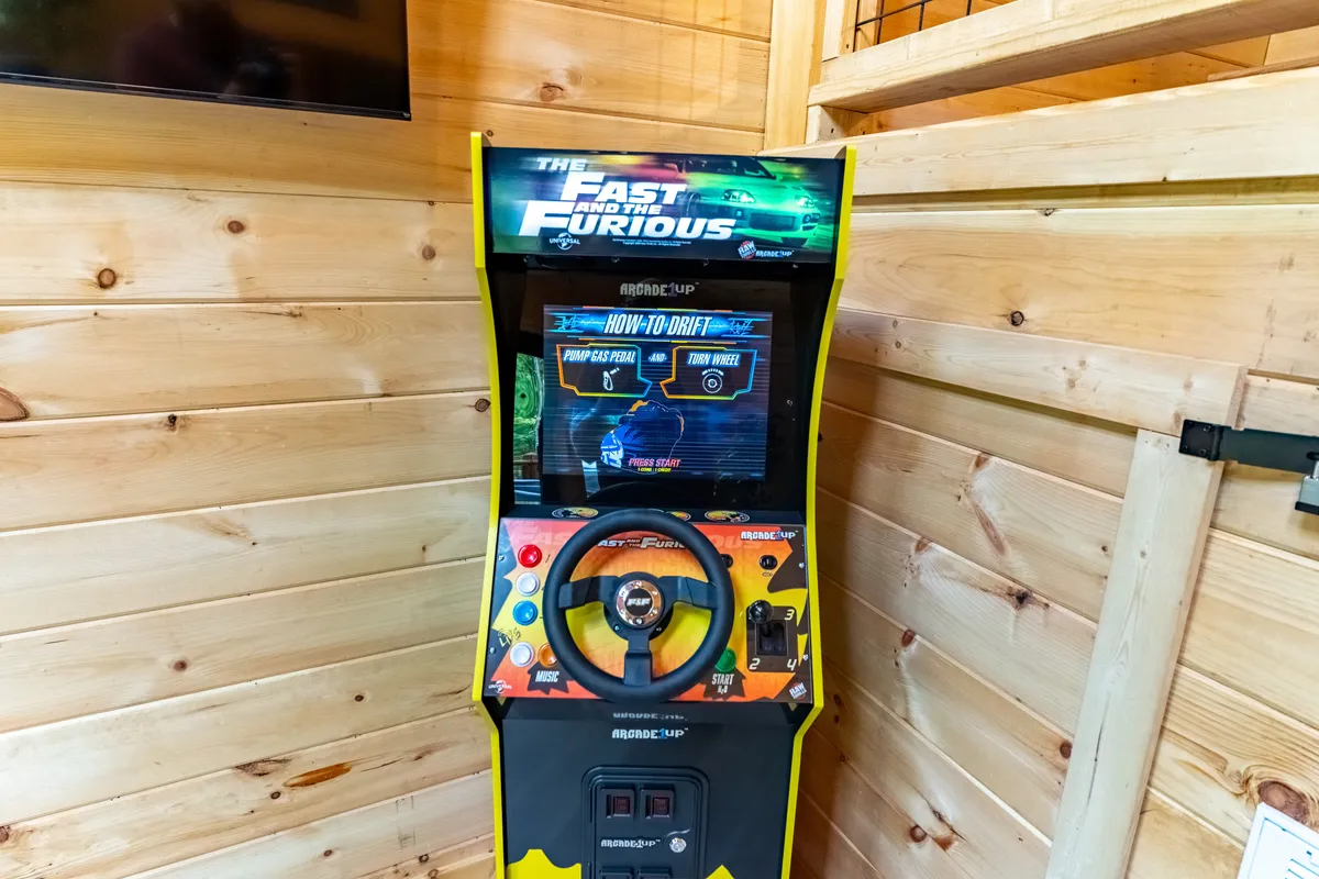 A cozy interior scene with an arcade machine against wooden walls. The setup is clearly designed for fun, friendly competition, and shared laughter—ideal for family tournaments and nostalgic gaming sessions after a day of exploring.