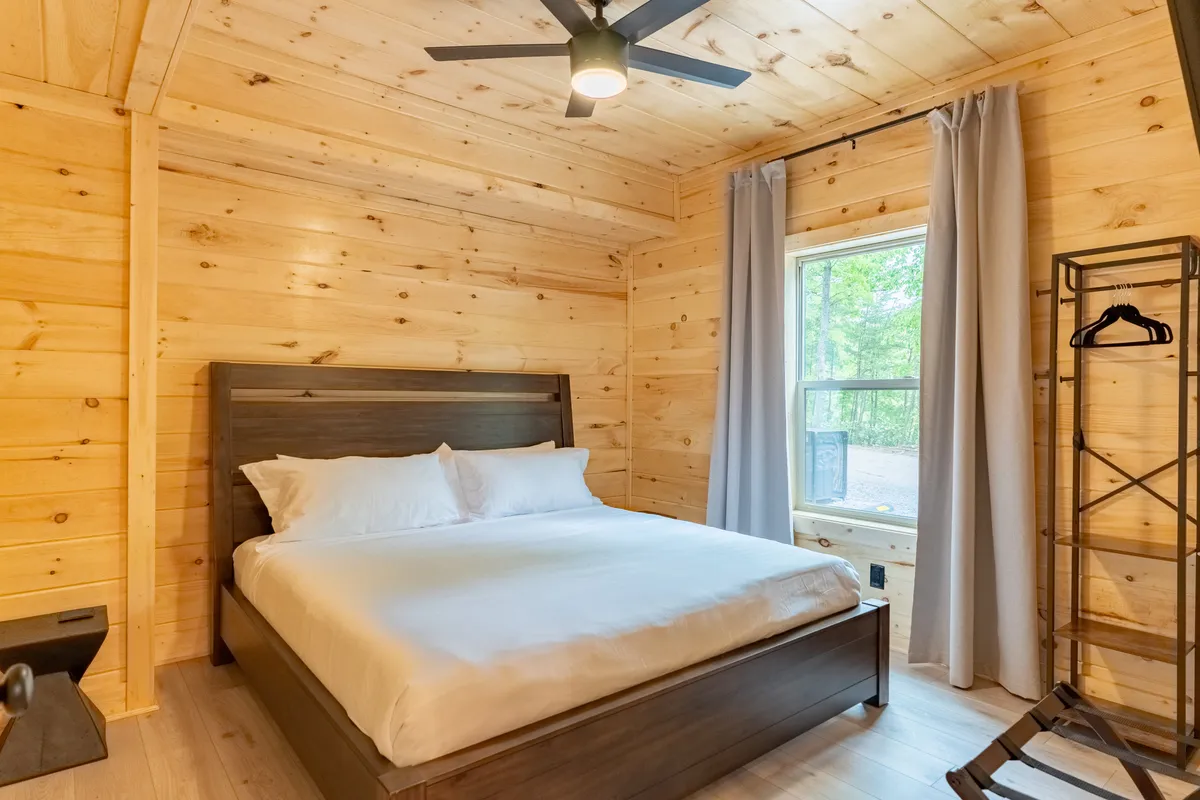 This image showcases a tranquil bedroom featuring a comfortable bed with crisp linens, a window with curtains letting in natural light, a nightstand, and a shelf. The overall mood is calm and restful, perfectly aligning with the luxurious king bedrooms described in the section.